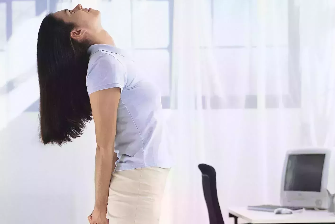 morning stretches – woman standing beside her desk doing chest opener stretch