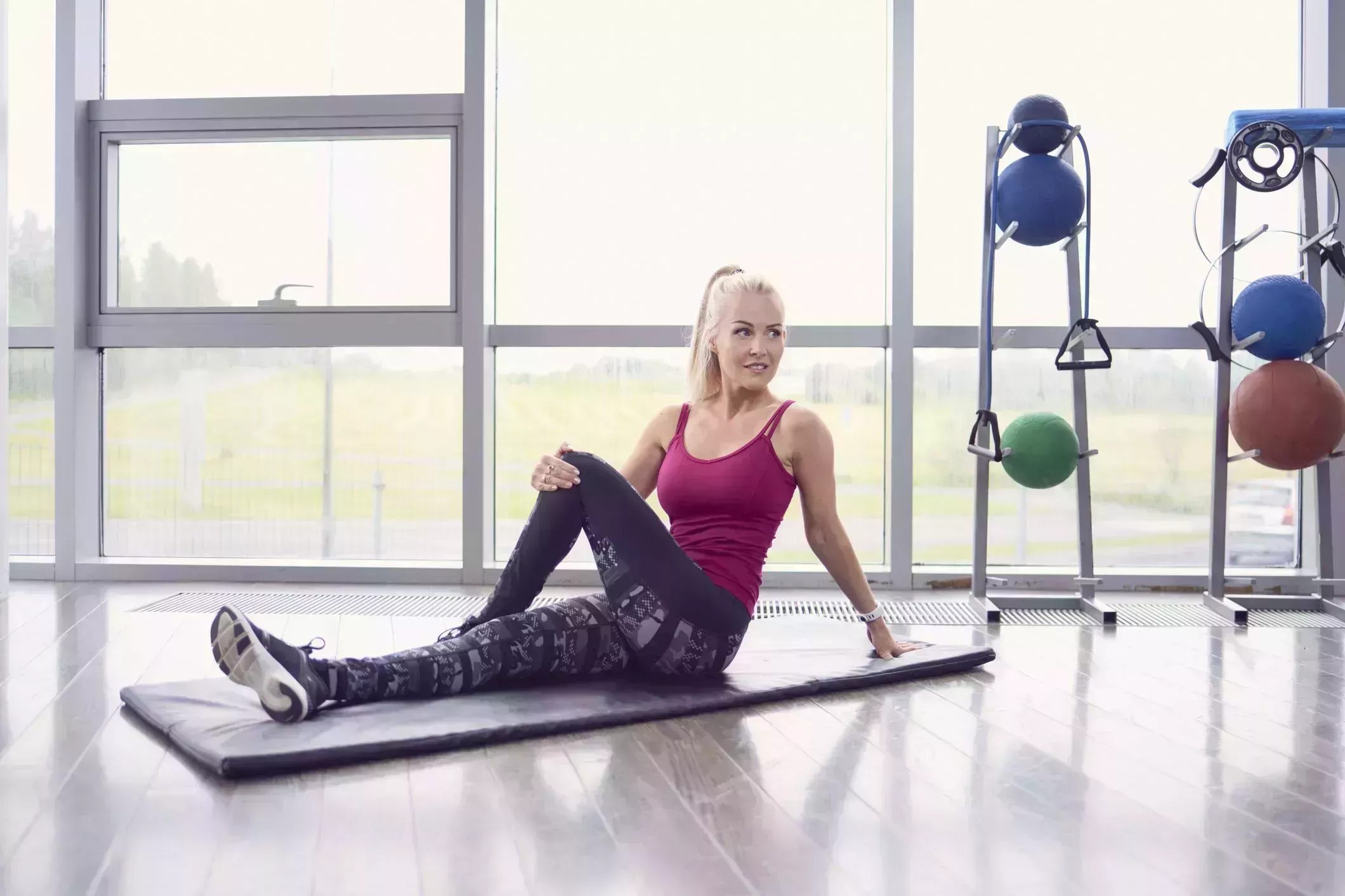 morning stretches – woman on an exercise mat in a gym doing a seated twist stretch